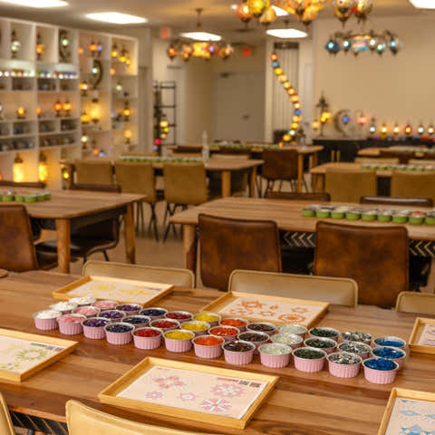 Spacious craft workshop with organized workstations, hanging mosaic lamps, and bead supplies